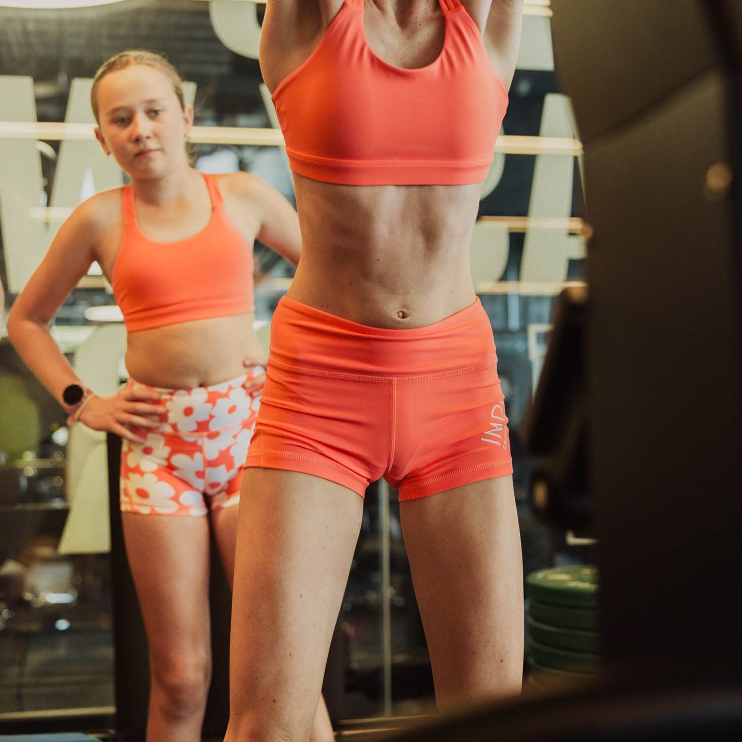 Woman in orange athletic wear lifting weights in a gym setting