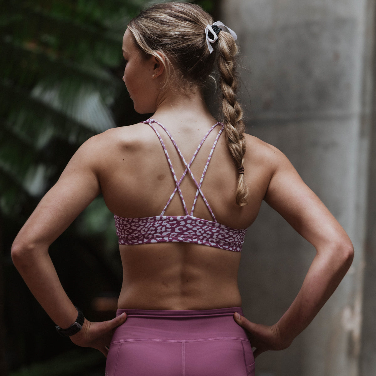 Person wearing a purple sports bra and leggings with a blurred background