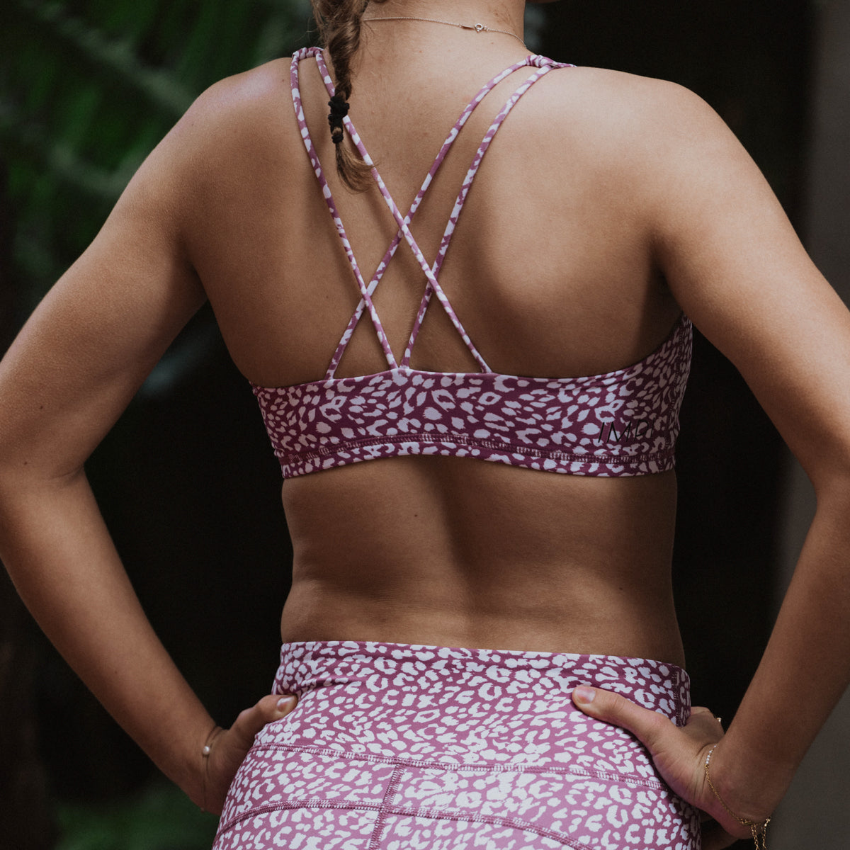 Person wearing a purple sports bra and leggings with a pattern.