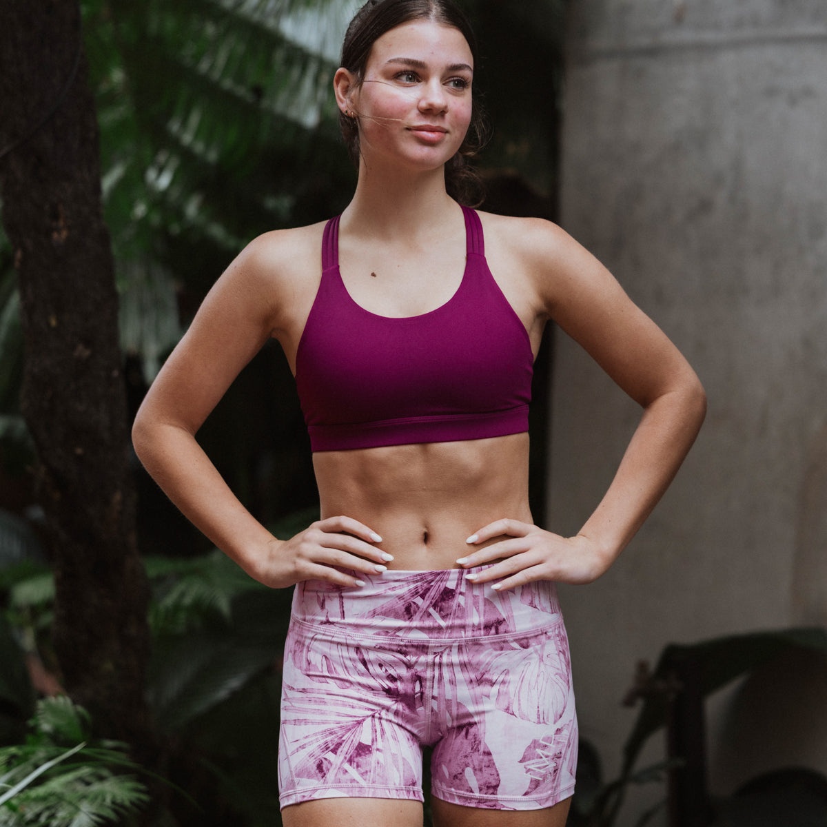 Woman wearing a purple sports bra and shorts in an outdoor setting