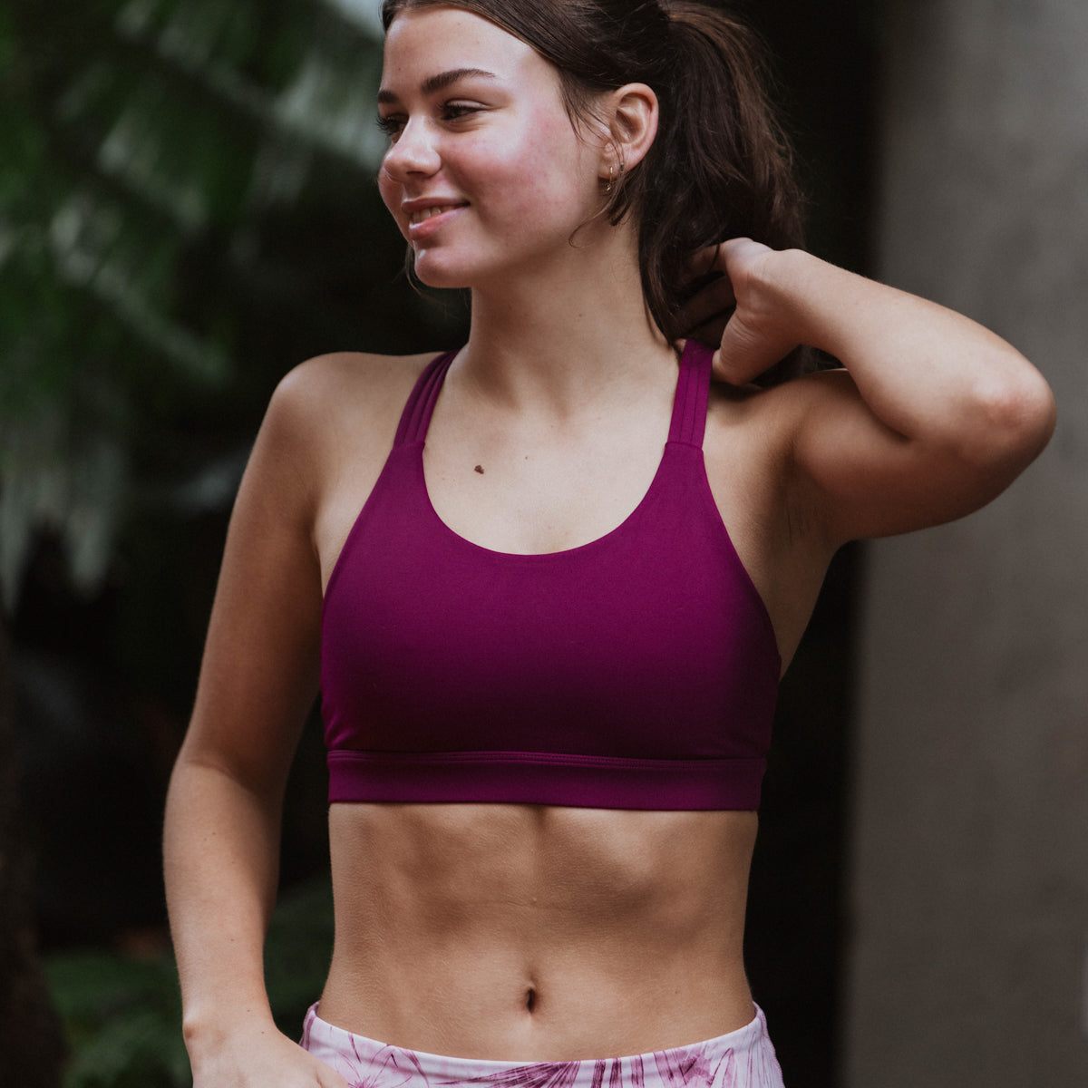 Woman wearing a purple sports bra and plaid shorts outdoors
