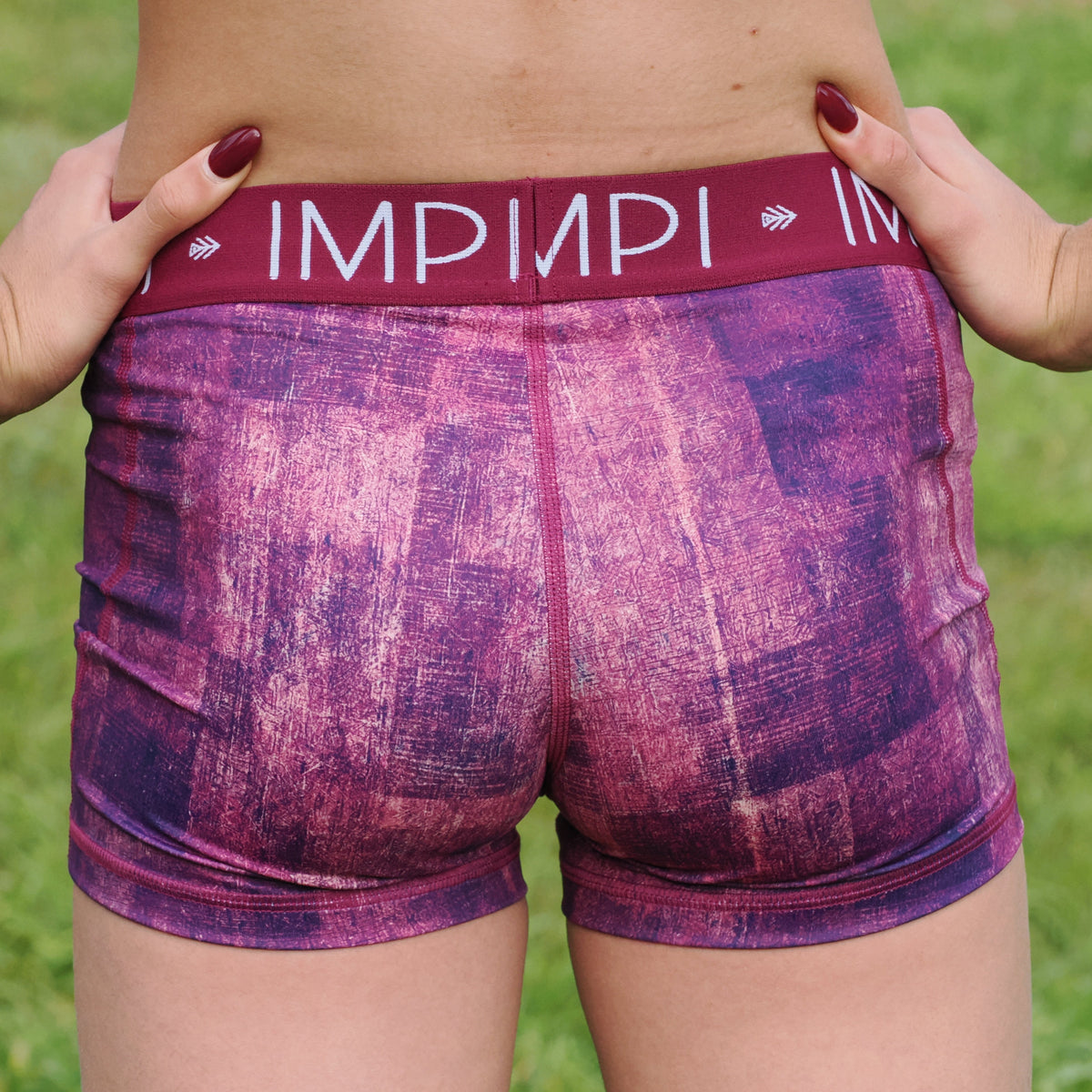 Person wearing purple patterned shorts with a brand logo on a grassy background