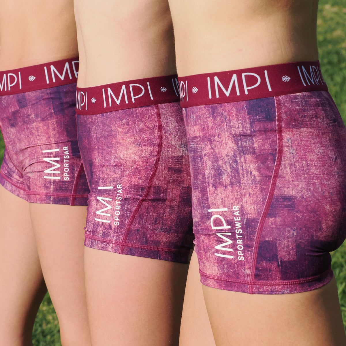 Purple boxer briefs with red waistband and &#39;IMPI&#39; branding on a grass background